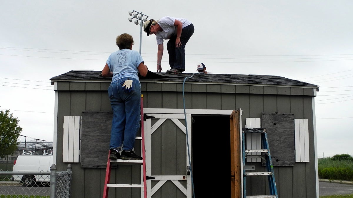  Chrissy Roche helps to rebuild the roof of a ball-field shed in Ventnor, N.J. She says volunteering helps ease the stress and frustration she feels as she rebuilds her own home, which flooded during Superstorm Sandy. (Tracey Samuelson/WHYY) 