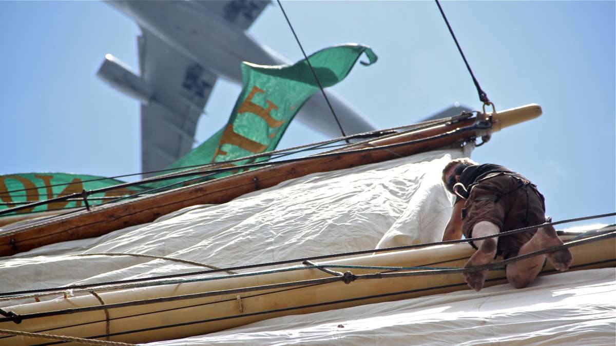 Emil Visby climbs high into the rigging to free a sail. (Emma Lee/WHYY)