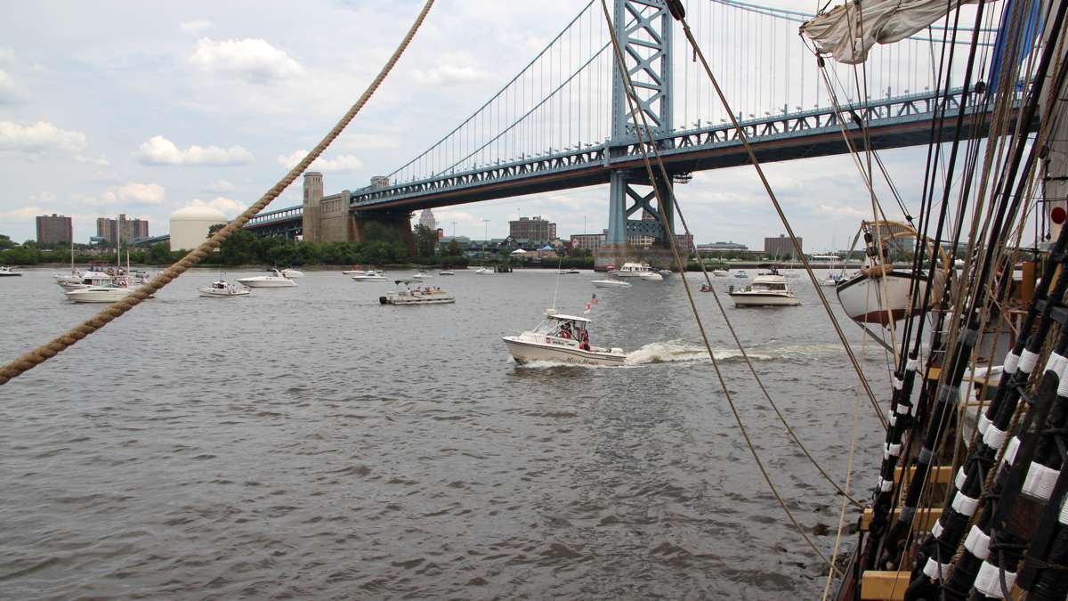 Small pleasure boats gather under the Ben Franklin Bridge to watch the arrival of the tall ships. (Emma Lee/WHYY)