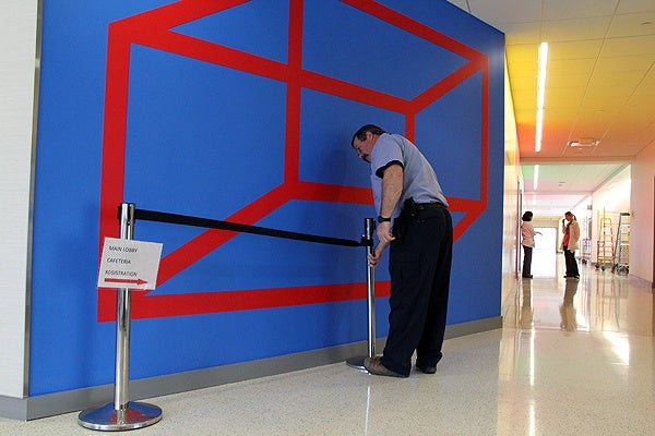 <p>A custodian arranges a temporary cordon around a work by Sol LeWitt at Einstein Medical Center. Montgomery, to keep it pristine until the unveiling on Wednesday. (Emma Lee/for NewsWorks)</p>
