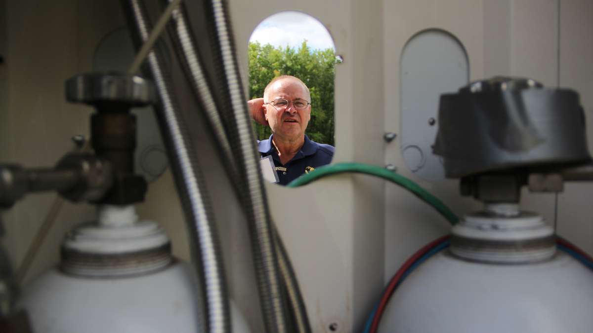 Mike Stanski examines a portable power station that stores the product of solar and wind power in hydrogen tanks. The Joule Box is marketed as an alternative to gas powered generators. (Emma Lee/WHYY)