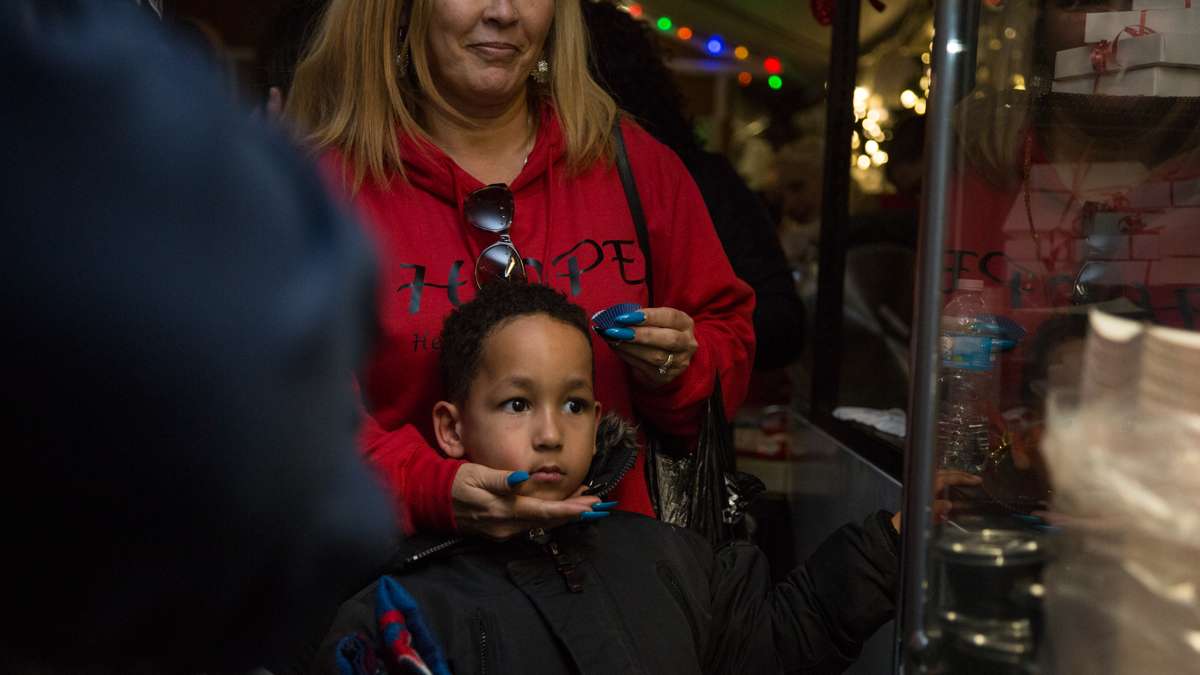 Visitors watch intently as a man makes and fries donuts at The Franklin Square Holiday and Light Festival. The festival runs November 10 through December 31 and is free to the public.