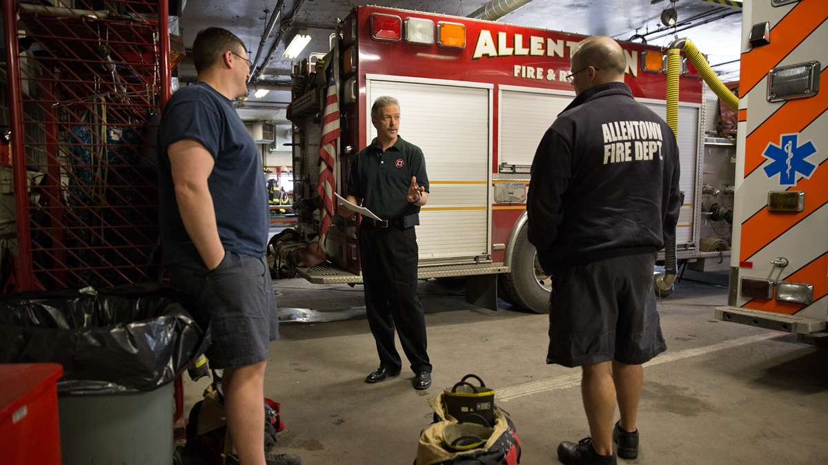 three firefighters standing by fire truck