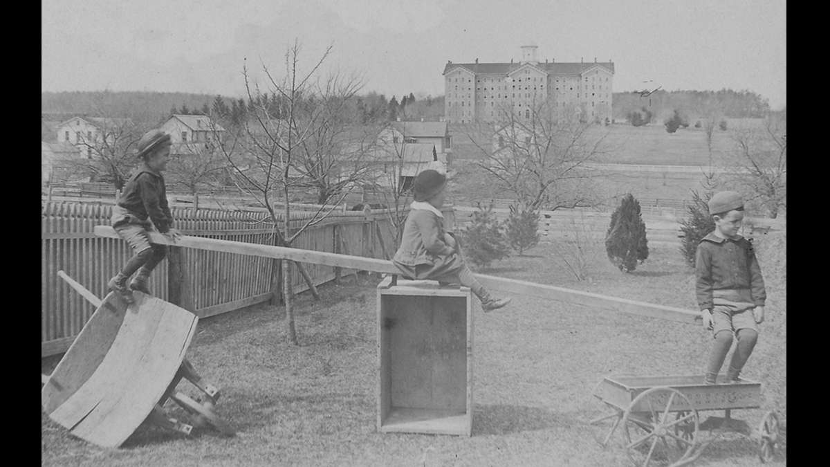 Children play near Pugh Street and Beaver Avenue in State College, Pennsylvania with the original Old Main in the distance circa 1885. (Image courtesy of the Centre County Historical Society)