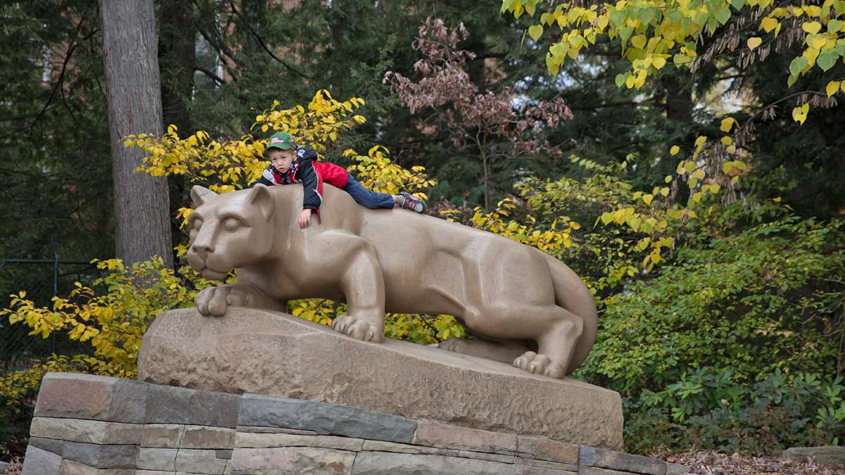Brayden King, 4, lies on top of the Nittany Lion Shrine as his grandmother looks on. (Lindsay Lazarski/WHYY)