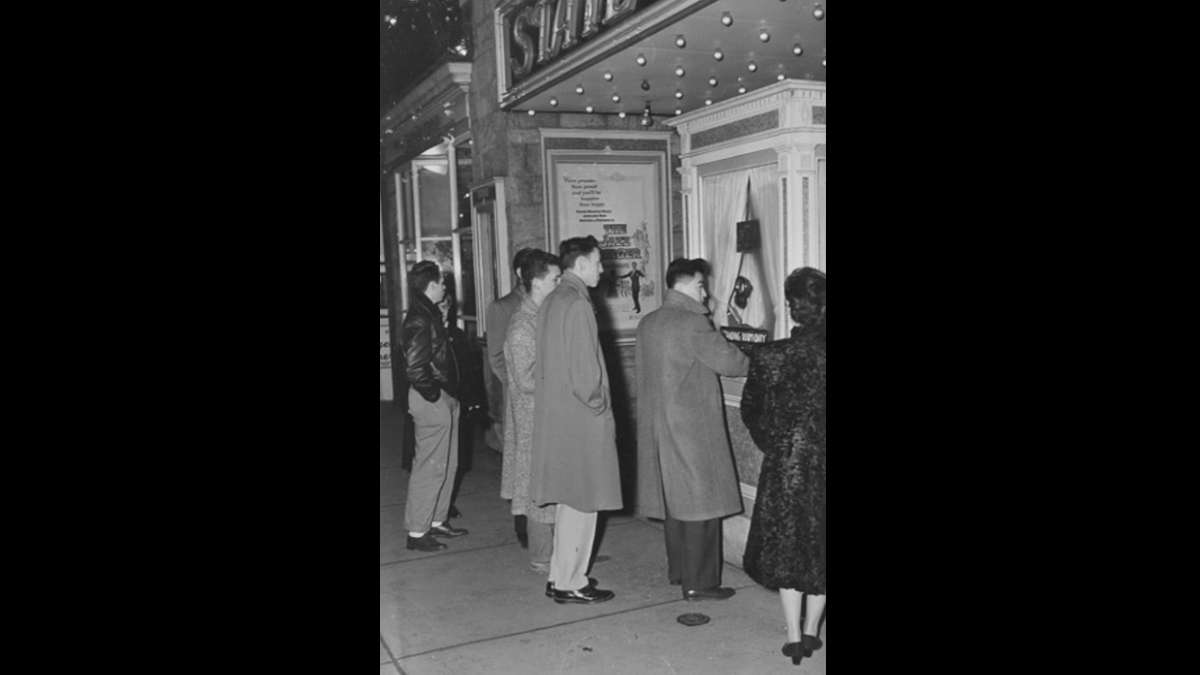 Patrons wait in line for tickets at The State Theater.  Warner Brothers opened the theater in 1938. The company tested four different films each week and charged 30 cents for a matinee, 35 cents for an evening feature. (Image courtesy of the Penn State University Archives)