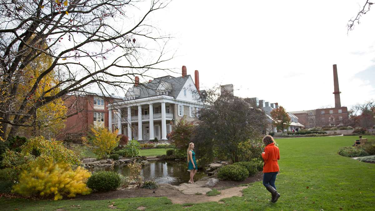 Senior Leah Eder from Lansdale, Pennsylvania poses for a graduation portrait in front of the Hintz Family Alumni Center as sophomore Brianna Basile from Macungie, Pa. takes her photo. (Lindsay Lazarski/WHYY)