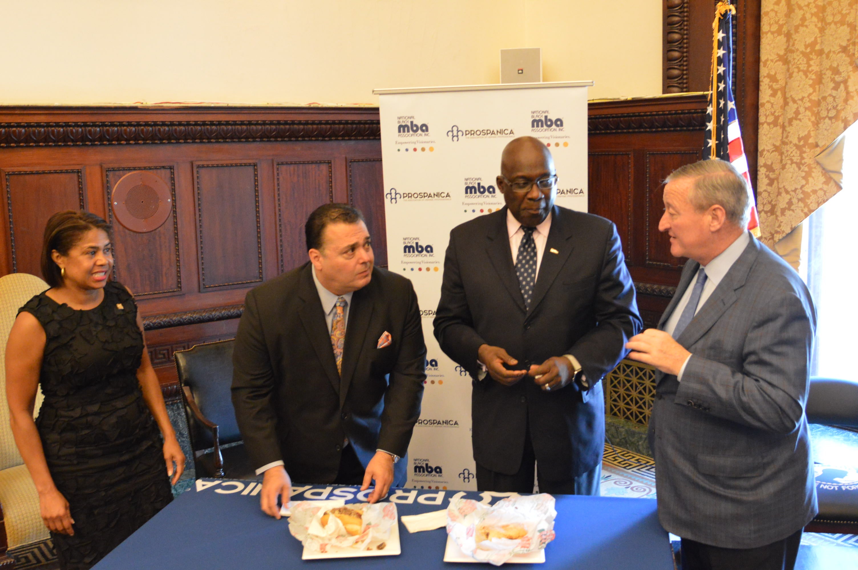  From left, Julie Coker Graham of the Convention and Visitors Bureau, Thomas Salvino of Prospanica and Jesse Tyson of the National Black MBA Association join Mayor Jim Kenney talk cheesesteaks at the announcement of the September conference. (Tom MacDonald/WHYY)  