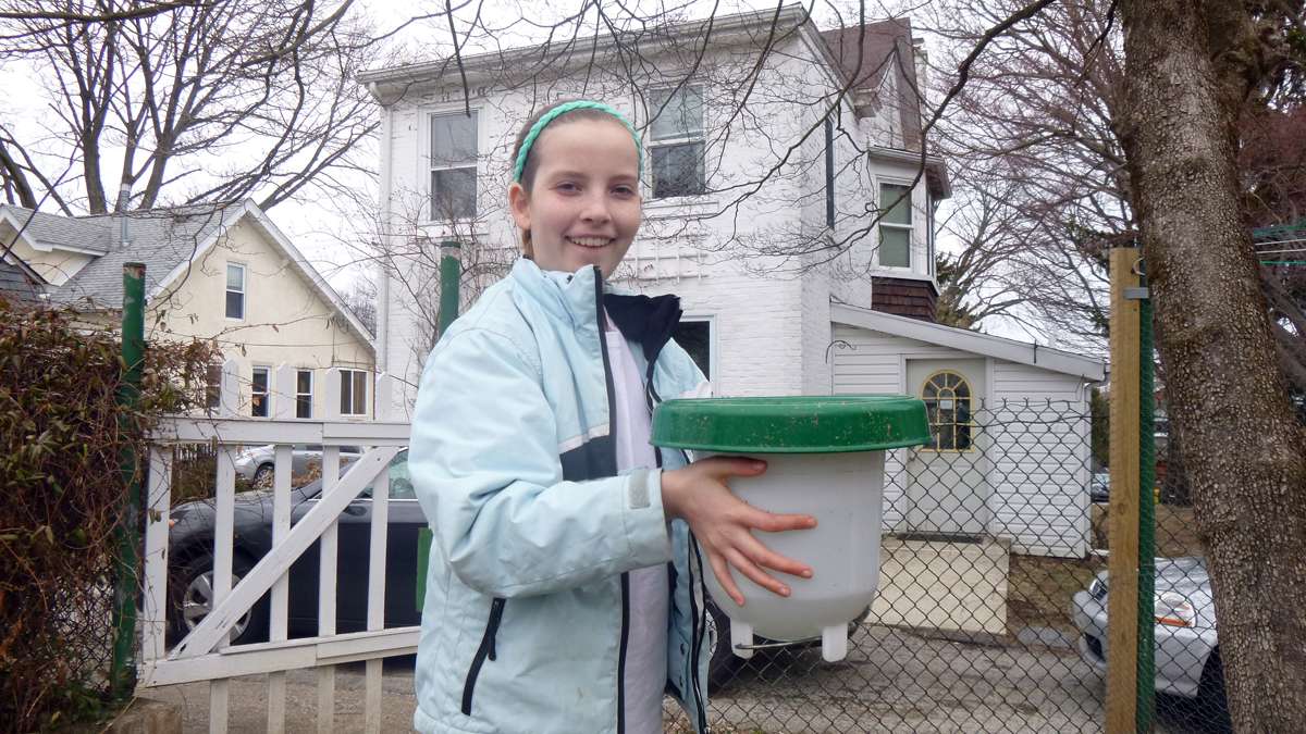 Ariadne Marg-Bracken, 13, with the chicken coop's watering trough. (Jennifer Lynn/WHYY)
