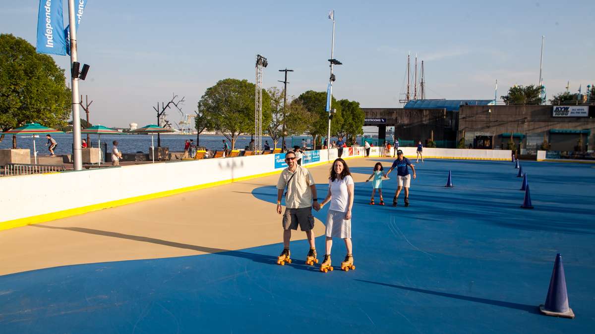 Rachael and Michael Smollen of Bucks County skate at the River Rink while their daughter follows behind with a staff member.