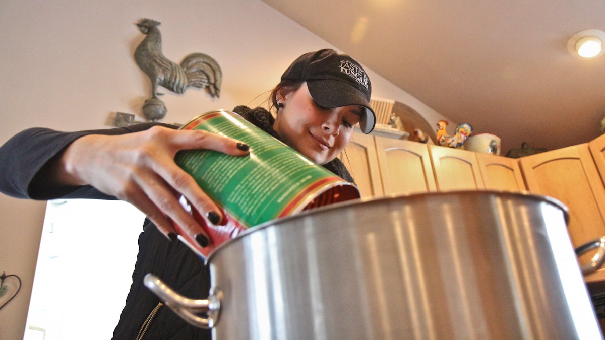 Katie Robbins add Contadina crushed tomatoes to the batch of Taste of Tuscany pasta sauce. (Kimberly Paynter/WHYY)