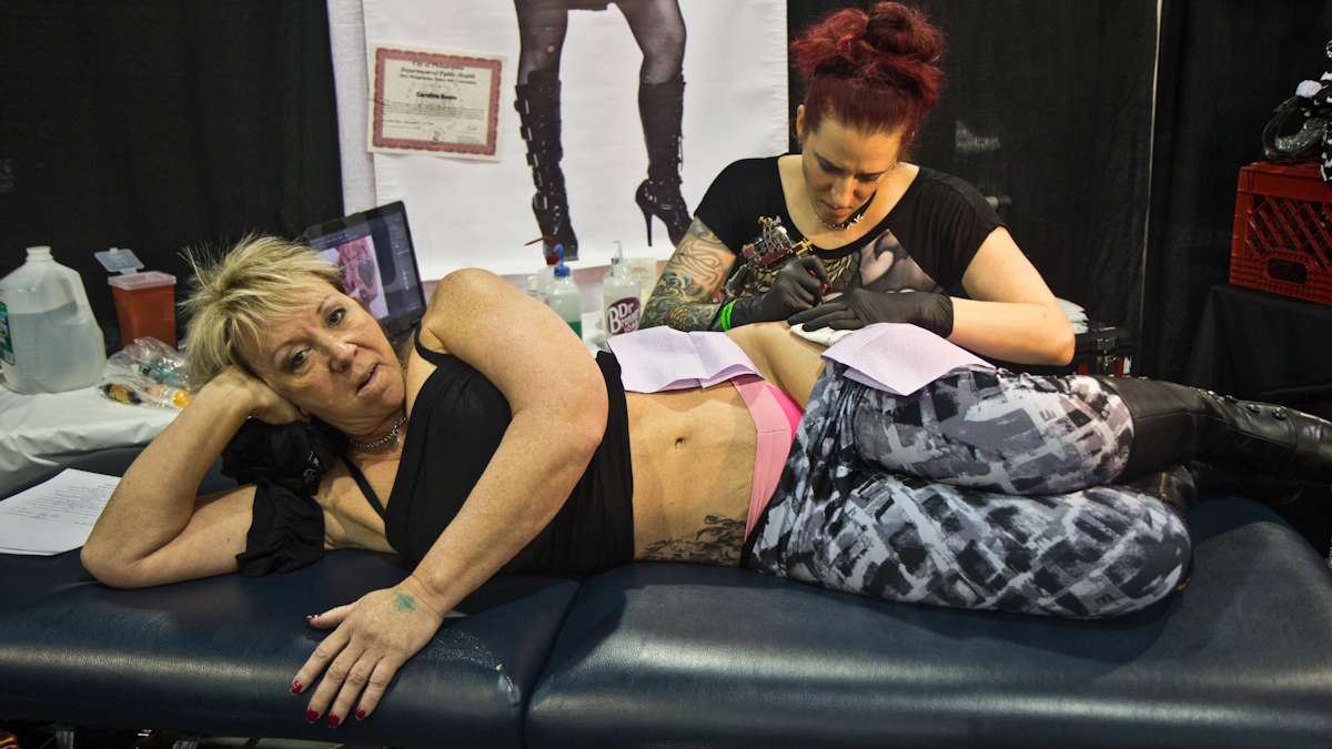 Artist Caroline Anne Evans tattoos on Jenny King a locket and three keys that represent King’s children. (Kimberly Paynter/WHYY)