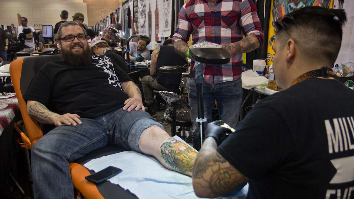 Artist Tom Aladna tattoos a deer on Chet Wescoat because of Wescoat’s love of hunting. (Kimberly Paynter/WHYY)