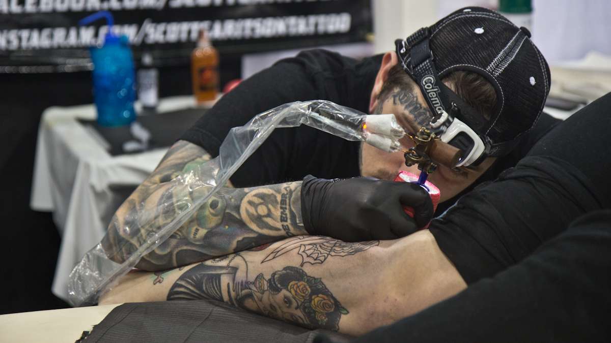 Ashley Hatton receives a butterfly dagger tattoo from artist Scott Garitson. (Kimberly Paynter/WHYY)