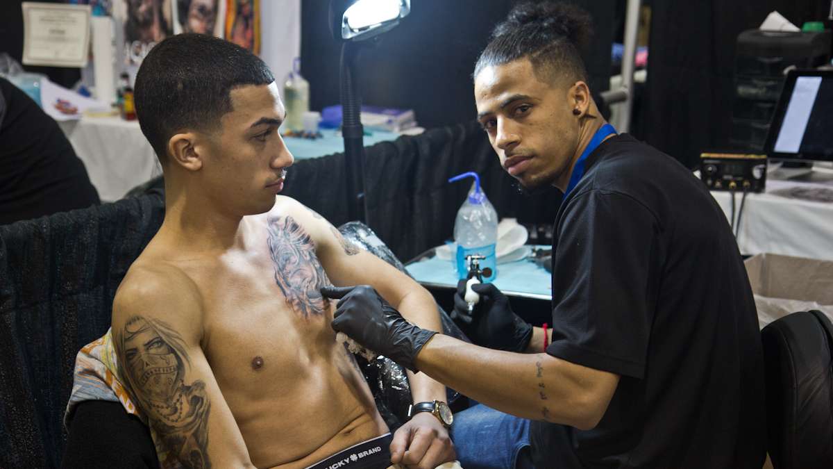 Artist Elton Duarte tattoos a realistic bio-organic creature on Hector Hernandez, a fan of the artist. (Kimberly Paynter/WHYY)