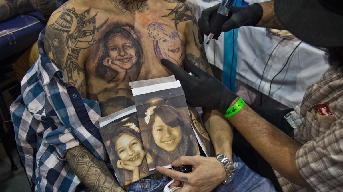 Artist Miguel Camarillo tattoos images of Antion Sanchez’s daughter onto his chest. (Kimberly Paynter/WHYY)