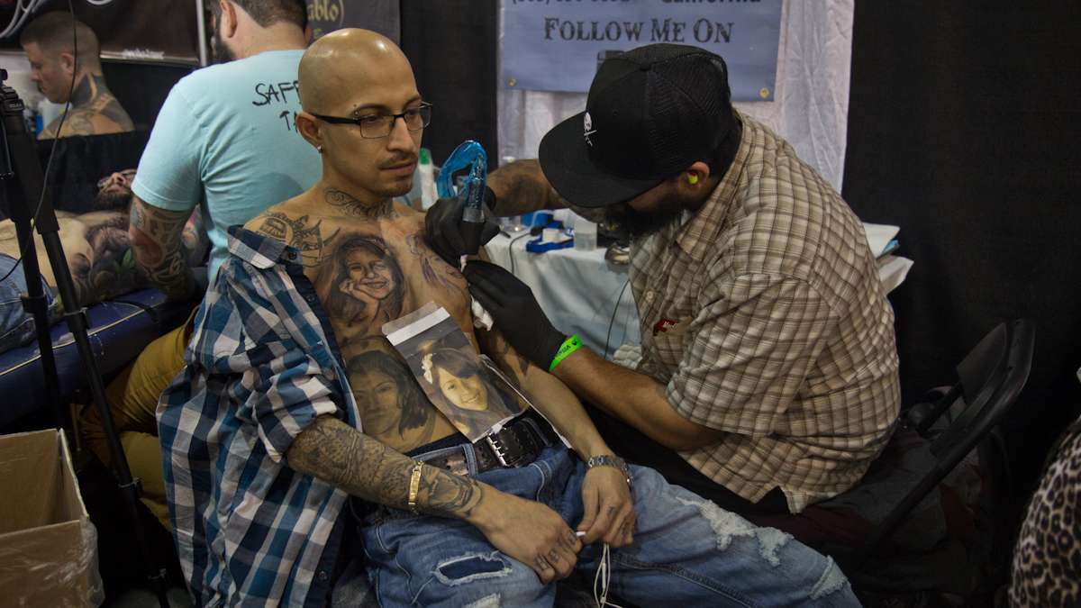 Artist Miguel Camarillo tattoos images of Antion Sanchez’s daughter onto his chest. (Kimberly Paynter/WHYY)