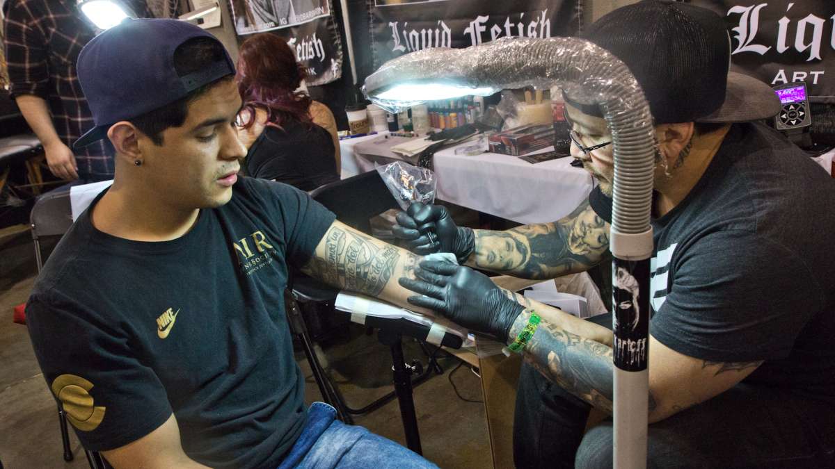 Artist Greg Summi cleans up a tattoo for Diego Reyes.