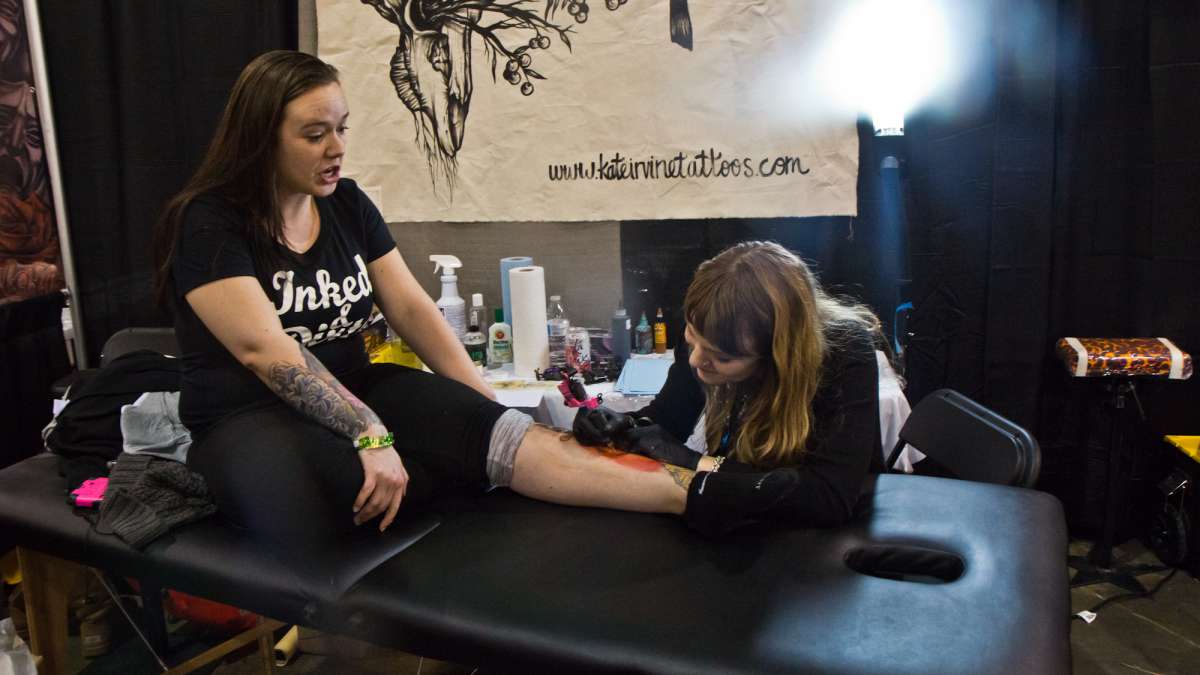 Kate Irvine tattoos a dagger piercing a peach on Savannah Buckmann.