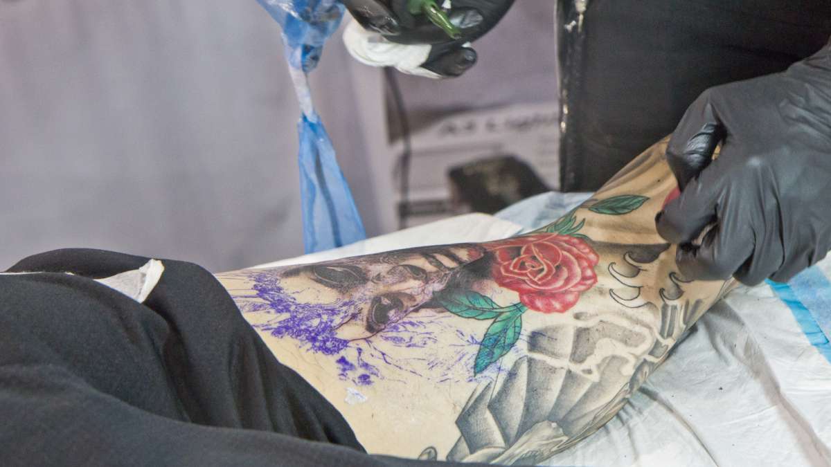 Philipus Murdijanto tattoos a masquerade girl onto a customer.