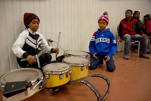 Tawanda Jones' son Requan, 8, (left) helps keep the beat for the Camden Sophisticated Sisters.  (Lindsay Lazarski/WHYY)
