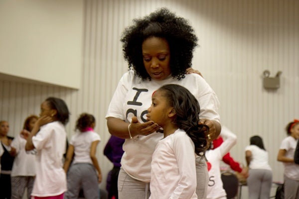 Tawanda Jones, leader of Camden Sophisticated Sisters, with Da'Anah Harper, 6, reminds the team members to carry themselves with confidence.  (Lindsay Lazarski/WHYY)
