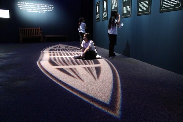 A 5th grader from Meredith Elementary School sits in a lifeboat of light at the Franklin Institute's Titanic exhibit. (Emma Lee/for NewsWorks)