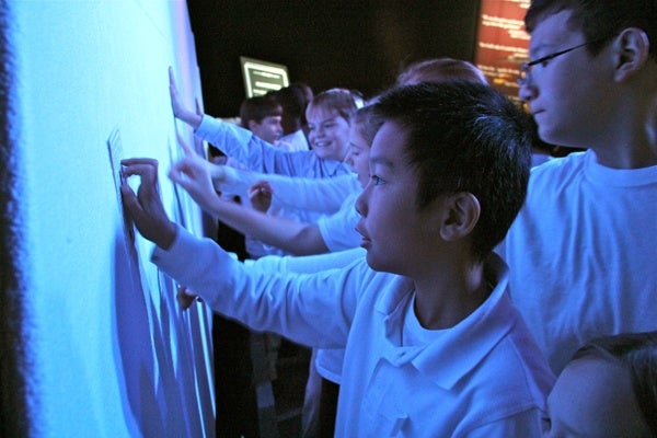 Victor Ung and his 5th grade classmates from Meredith Elementary School touch a representation of the iceberg that sank the Titanic. The wall is refrigerated to conjure the frigid conditions at the time of the sinking. (Emma Lee/for NewsWorks)