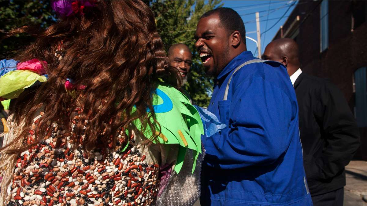 Jenny Drumgoole (aka Soxx) laughs with sanitation workers. Her specially made dress was covered in beans and pasta. (Brad Larrison/for NewsWorks)