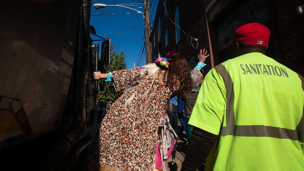 Soxx waves to sanitation workers from the back of a trash truck. (Brad Larrison/for NewsWorks)