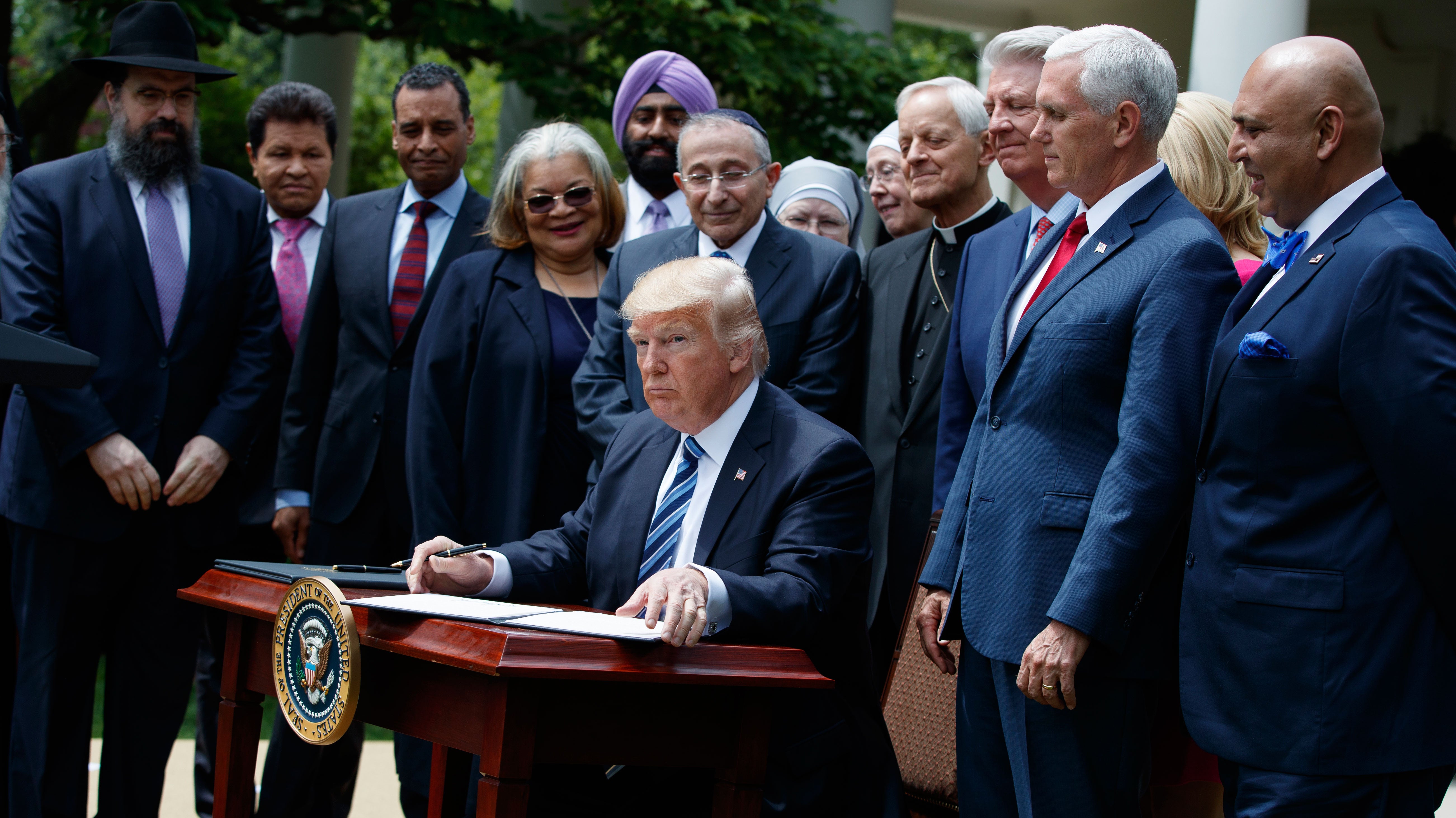  President Donald Trump signs an executive order aimed at easing an IRS rule limiting political activity for churches, Thursday, May 4, 2017, in the Rose Garden of the White House in Washington. (Evan Vucci/AP Photo) 