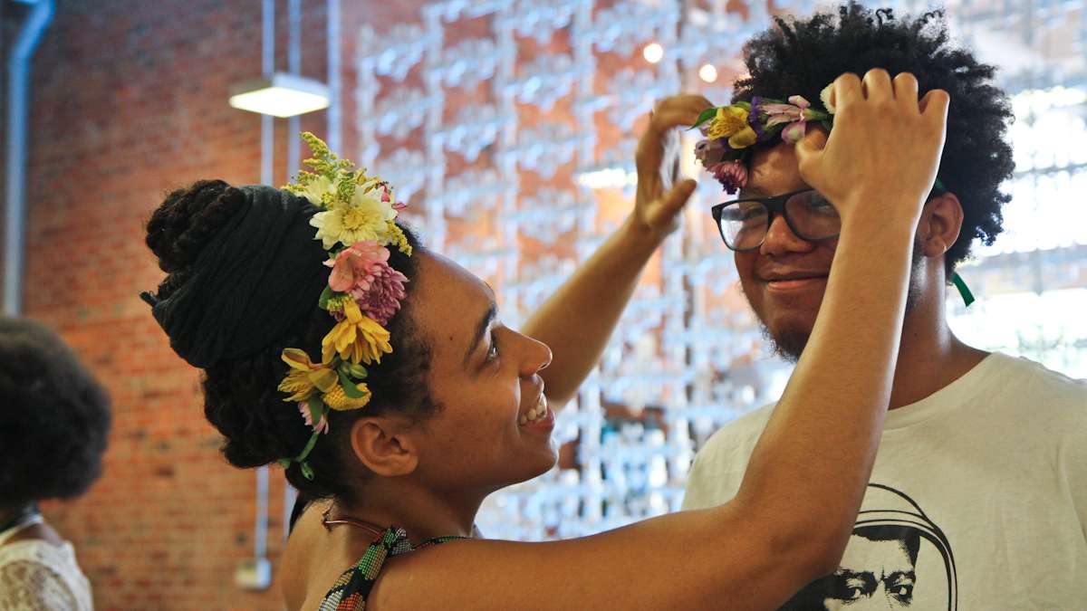 Helanah Warren crowns Kyree Frazier with flowers at the Kinks, Locks and Twists Conference Thursday afternoon. (Kimberly Paynter/WHYY)
