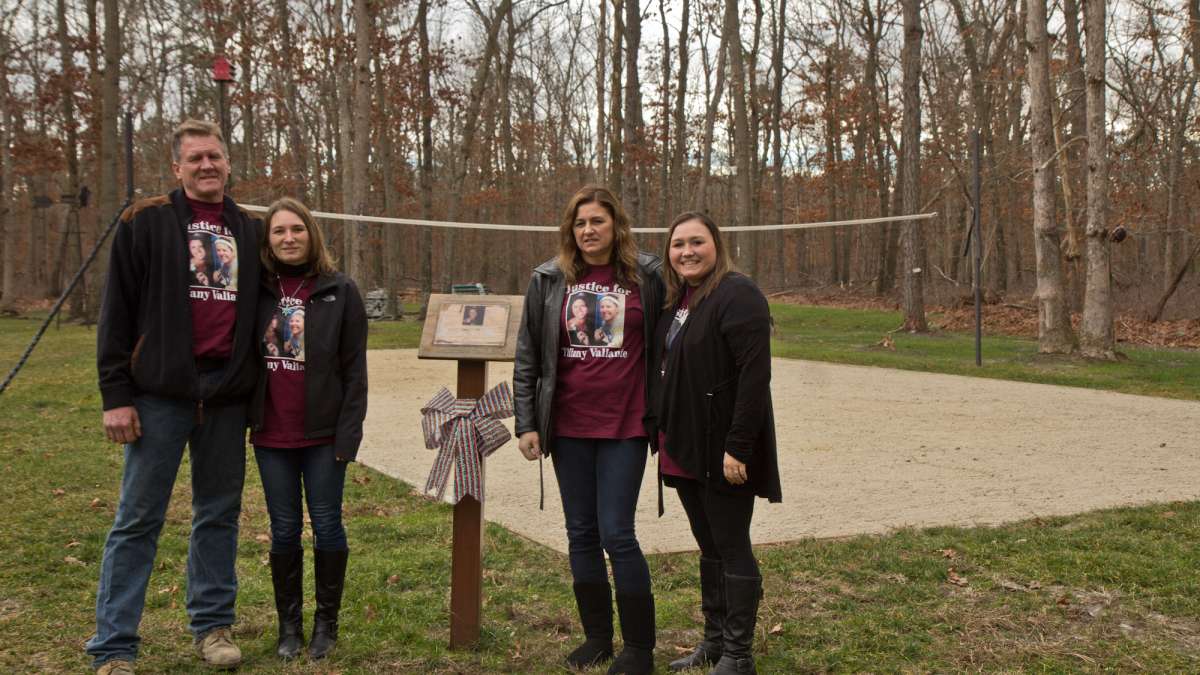 Tiffany’s father Stephen Valiante, sister Jessie Vallauri, mother Dianne Valiante, and sister Krystal Summerville stand in front of a volleyball court the family installed in the yard in memory of Tiffany.