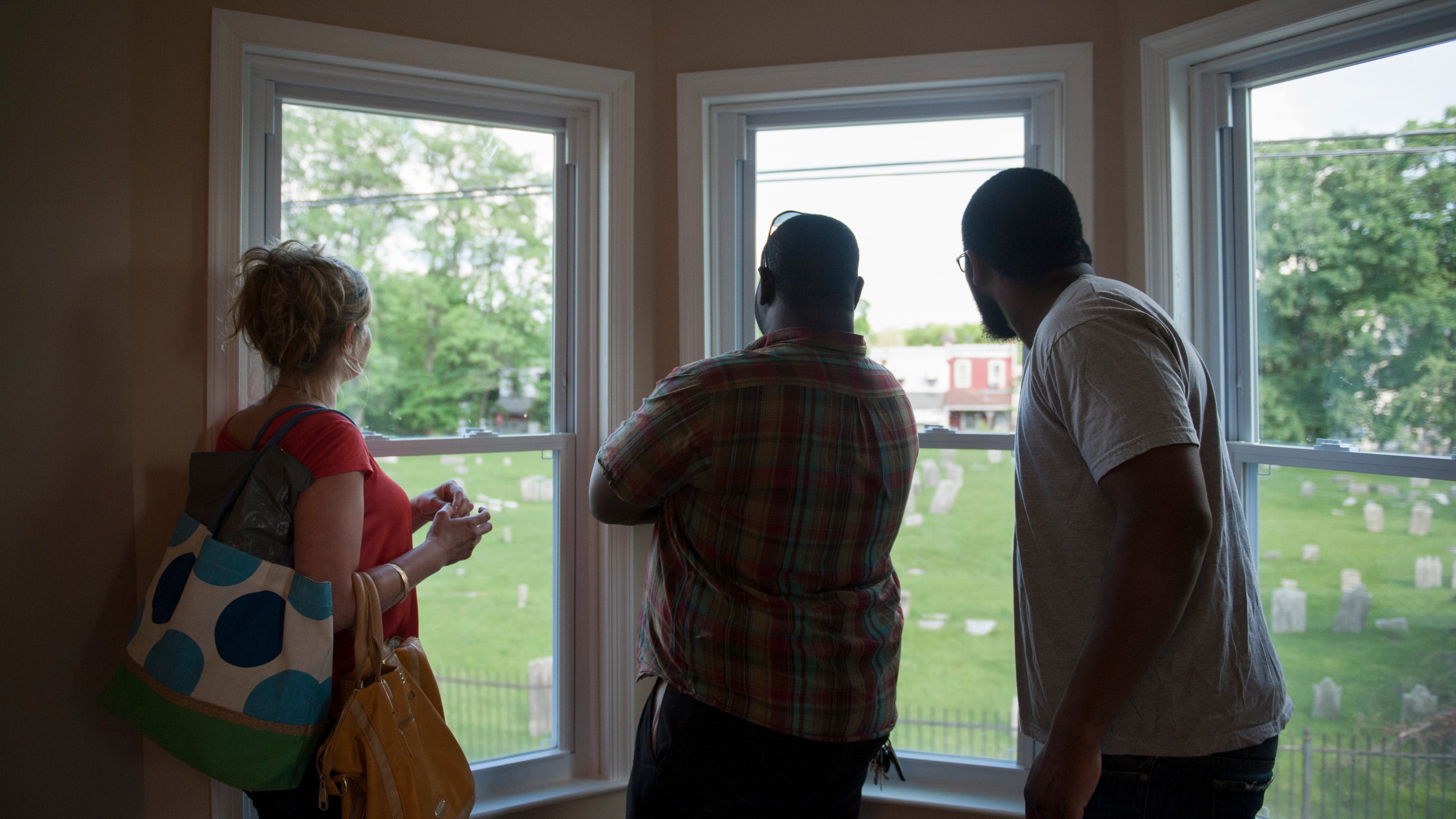 (From left) Elizabeth Mosell, of South Philadelphia, Jimmy Reed, of Mt. Airy, and Steven Halstead, of Mt. Airy, look out the windows in the master bedroom. Members of the Mt. Airy community were invited to view the newly renovated home at 59 E. Phil Ellena St. in Mt. Airy on Thursday evening, June 5, 2014. The property is the first to have been reclaimed by Mt. Airy USA under Pennsylvania's Conservatorship Act.
