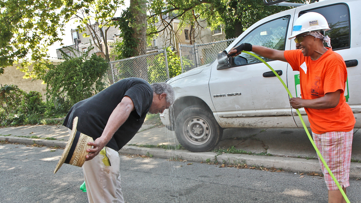  Gwendolyn Austin, President of the Cathedral Park Association, hoses down volunteer Kenneth Davenport. (Kimberly Paynter/WHYY) 