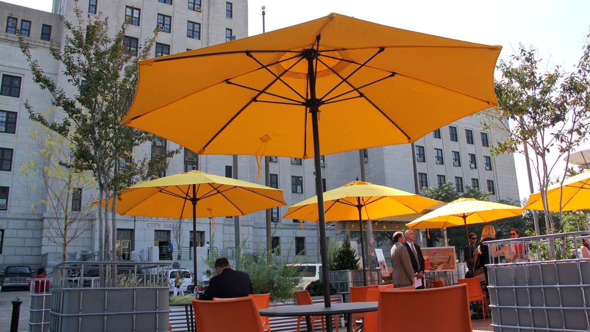 The new park offers plenty of seating under the shade of umbrellas and trees potted in bulk container totes. (Emma Lee/WHYY)