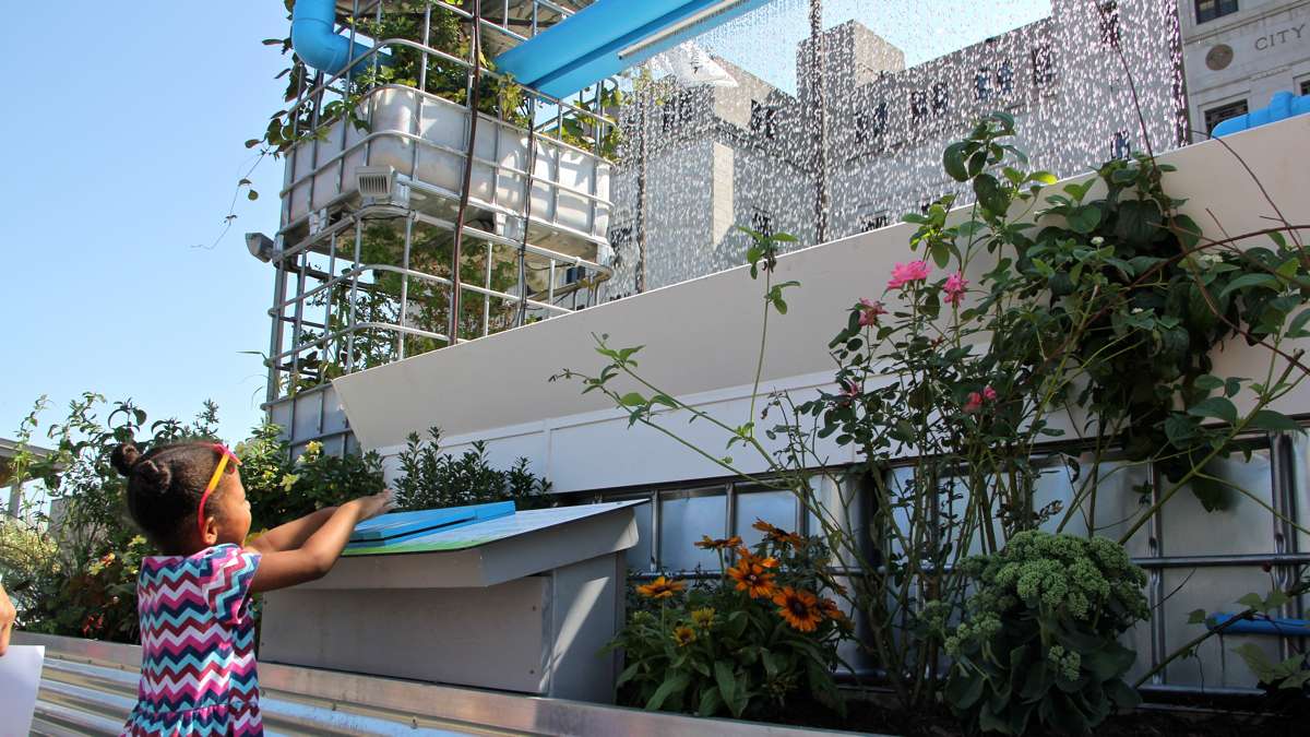 Layla Hamlet, 4, of Burlington experiments with the water organ at Roosevelt Plaza Park in Camden. The water organ allows users to alter the flow of the fountain by pressing keys. (Emma Lee/WHYY)