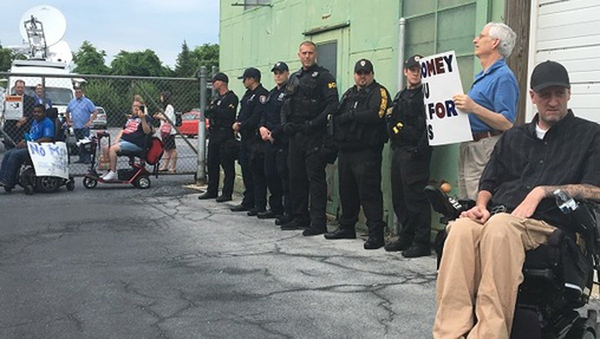 Police stand by as disabled protesters block a gate at the TV studio where Toomey held his town hall. Several of the protesters were later issued citations for trespassing. (AP Photo) 