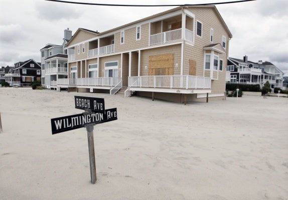 <p>A street sign is partially buried in sand Tuesday morning, Oct. 30, 2012, in Cape May, N.J., after a storm surge from Sandy pushed the Atlantic Ocean over the beach and across Beach Avenue. (AP Photo/Mel Evans)</p>
