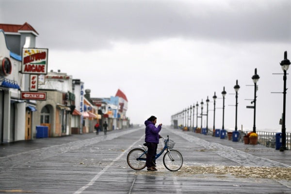 <p>A woman stands alone on the boardwalk Tuesday, Oct. 30, 2012, in Ocean City, N.J., as she photographs sea foam that washed up from the storm surge of Sandy. The storm that made landfall in New Jersey on Monday evening with 80 mph sustained winds killed at least 16 people in seven states, cut power to more than 7.4 million homes and businesses from the Carolinas to Ohio, caused scares at two nuclear power plants and stopped the presidential campaign cold. (AP Photo/Mel Evans)</p>

