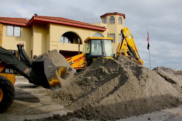 <p>Crews with backhoes on South Iroquois Avenue in Margate scoop sand off the street and return it to the beach. (Emma Lee/for NewsWorks)</p>

