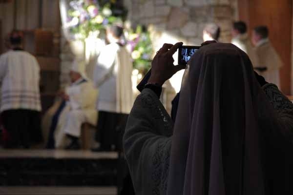 <p>A young woman uses her smartphone to record the installation of the 8th Bishop of Camden, Dennis J. Sullivan. (Emma Lee/for NewsWorks)</p>
