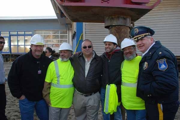 <p><p><span style="font-family: Tahoma, 'Sans Serif', Arial; font-size: small;">Seaside Heights Mayor William Akers (center) and Police Chief Thomas Boyd (right) stand with workers in front of the first pile of the new boardwalk. (Sandy Levine/for NewsWorks)</span></p></p>
