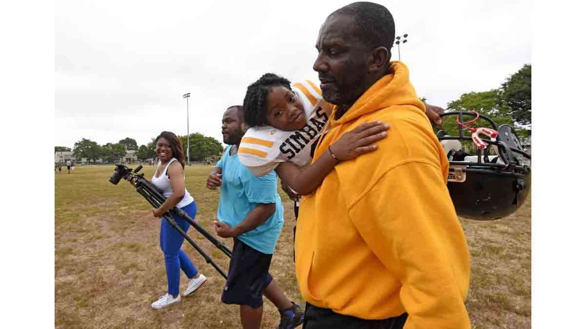 Simbas coach Orlando Council-Pettigrew carries Janiyah Hill off the field; at left is Hill's mother, Renekia Robinson; and in the middle is parent Christopher Johnson, whose son is also on the team.