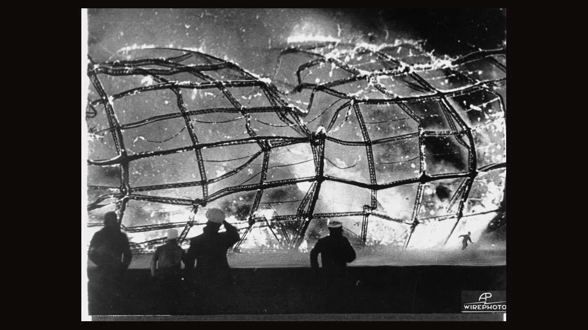 The burning Hindenburg is reduced to ruins as a survivor, lower right hand corner, runs to safety, May 6, 1937, after it exploded on mooring at Lakehurst Naval Air Station in New Jersey.