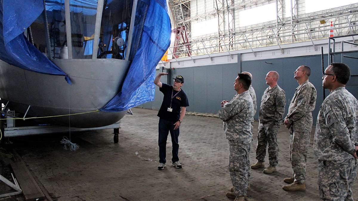 Kevin Mulligan, a volunteer with the Navy Lakehurst Historical Society, tells tour-goers about a reproduction of the control gondola of the Hindenburg, which was created for a 1975 movie about the disaster. The historically accurate prop is housed in Hangar 1, and covered in a tarp to avoid potential damage from leaks.