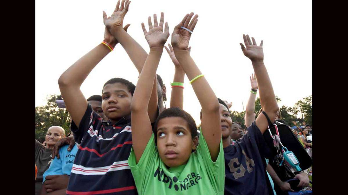 On August 20 at Von Nieda Park, Festival of Life attendees raise their arms while Jonathan Shuttlesworth preaches.