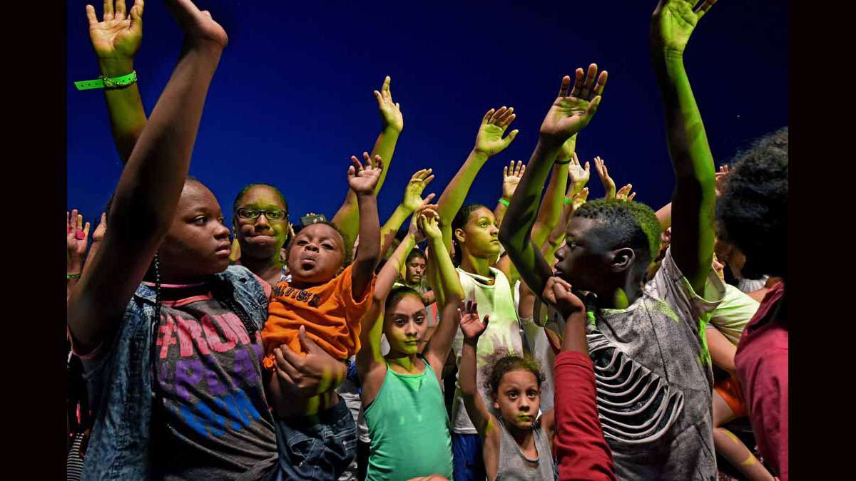 On August 20 at Von Nieda Park, Festival of Life attendees raise their arms while Jonathan Shuttlesworth preaches.