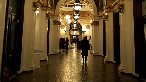 A man walks down a hall toward the light of the Capitol rotunda