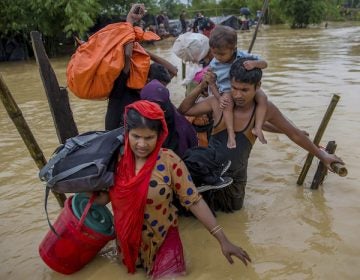 In this file photo, Rohingya Muslims, who crossed over from Myanmar into Bangladesh, use a makeshift footbridge as they carry their children and belongings after their camp was inundated with rain water near Balukhali refugee camp, Bangladesh, Tuesday, Sept. 19, 2017. With a mass exodus of Rohingya Muslims sparking accusations of ethnic cleansing from the United Nations and others. (Dar Yasin/AP Photo)